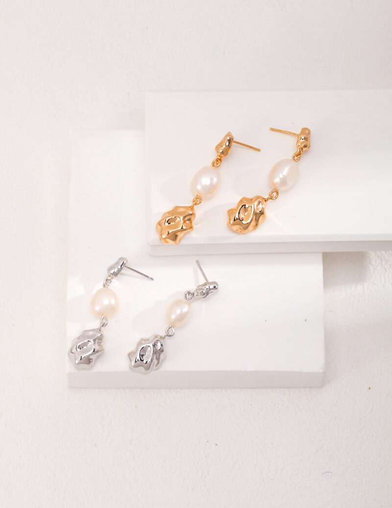 A collection of earrings displayed on a white stepped platform, featuring designs with gold pearl jewelry and sterling pearl jewelry accents. Elegant pearl jewelry