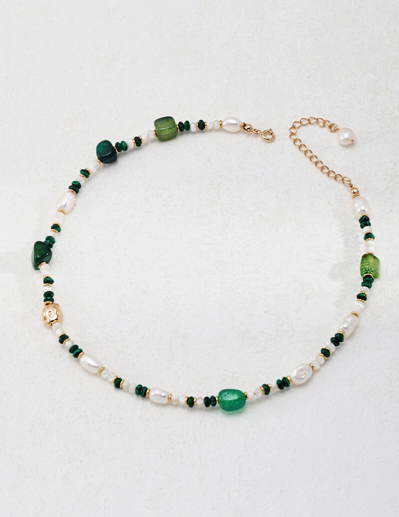 Elegant necklace featuring a sequence of gemstones and freshwater pearls on a gold chain, with an adjustable clasp and an additional pearl accent. Elegant pearl jewelry