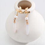 Elegant gold pearl jewelry earrings with a swan design, featuring freshwater pearls and white drop pendants.