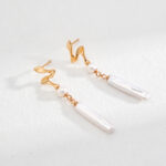 A pair of elegant earrings featuring twist hooks and dangling natural freshwater pearls, displayed against a textured white background. Elegant pearl jewelry