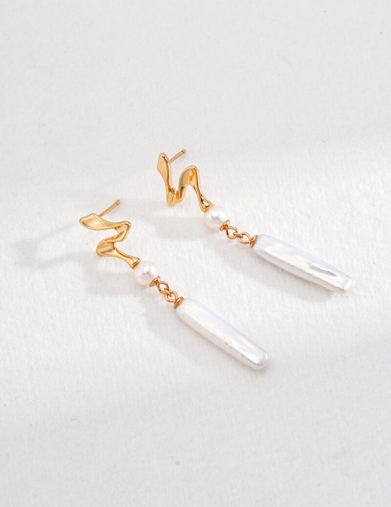 A pair of elegant earrings featuring twist hooks and dangling natural freshwater pearls, displayed against a textured white background. Elegant pearl jewelry