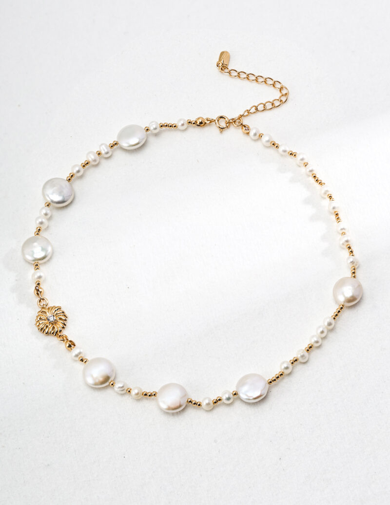 Elegant o_1hsn3fdmf1ut1alp1qnb1euasm35 necklace with alternating large and small pearls linked by delicate gold vermeil chains, featuring a gold vermeil clasp and small leaf charm from the floral series, displayed on a light Elegant pearl jewelry