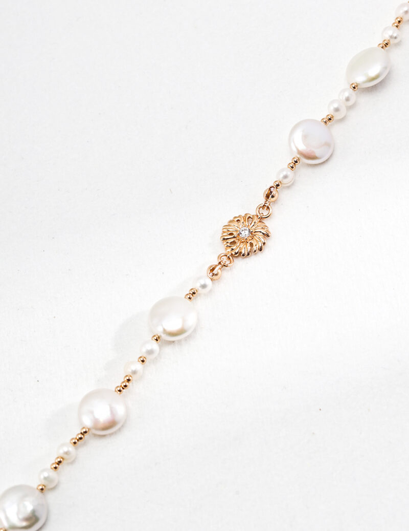 A delicate bracelet featuring a string of alternating large and small pearls with a gold vermeil sunburst charm centered on a plain white background. Elegant pearl jewelry