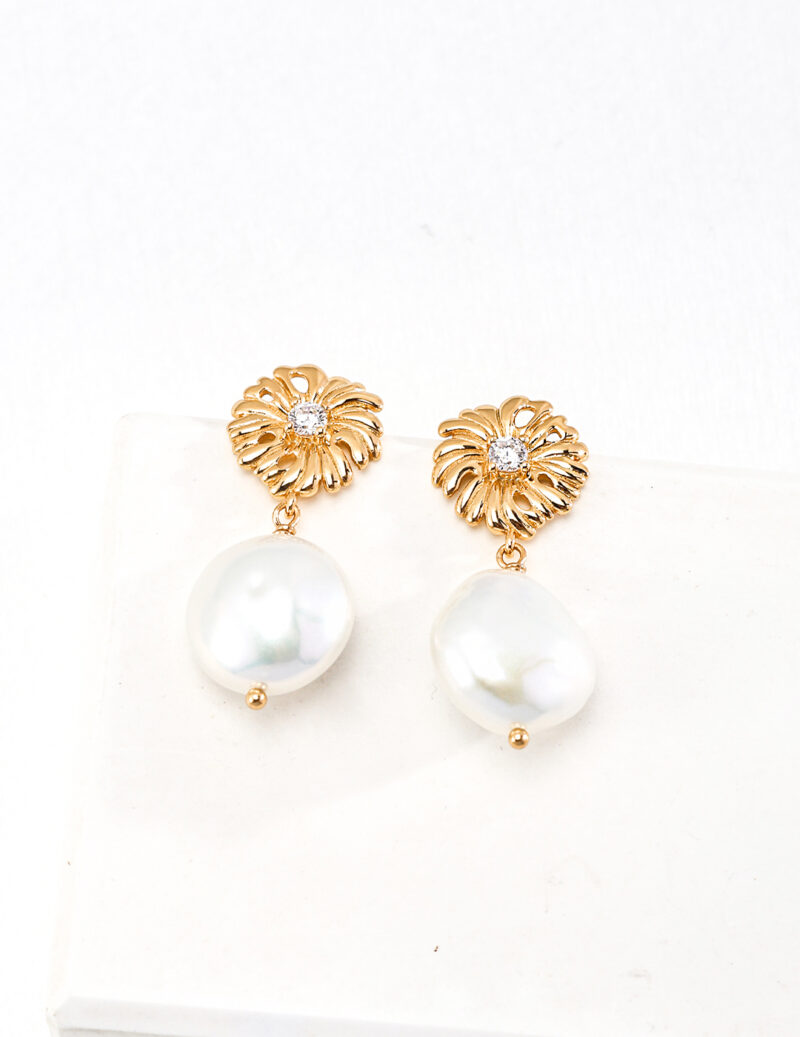 A pair of elegant 18k Gold Vermeil earrings with intricate floral designs at the top, featuring shimmering white gemstones in the center. Below each floral design hangs a large, lustrous white pearl, giving these o_1htim9ik21tihivc4mt8gd13o71 from our Floral Series a luxurious and classic appearance. Elegant pearl jewelry