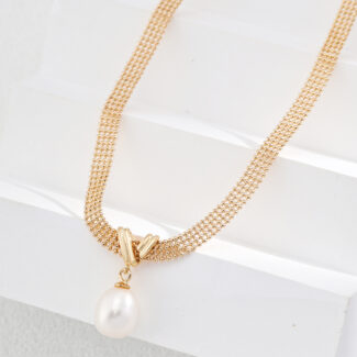 A gold necklace (product: o_1i0fcngqa46hech98l1l221c7f1) with a delicate chain and a single, large, teardrop-shaped pearl pendant is displayed on a white, textured background. The chain features intricate lace-like links in 18k Gold Vermeil, adding to its elegance, and the pearl has a smooth, lustrous surface. Elegant pearl jewelry