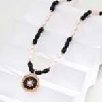 Introducing the o_1iac7vg14r7d1vpg5oi1f6i1lcg2, a captivating Black Onyx necklace adorned with alternating black and white beads, featuring a circular pendant with a central gemstone design, elegantly displayed on staggered white steps. Elegant pearl jewelry